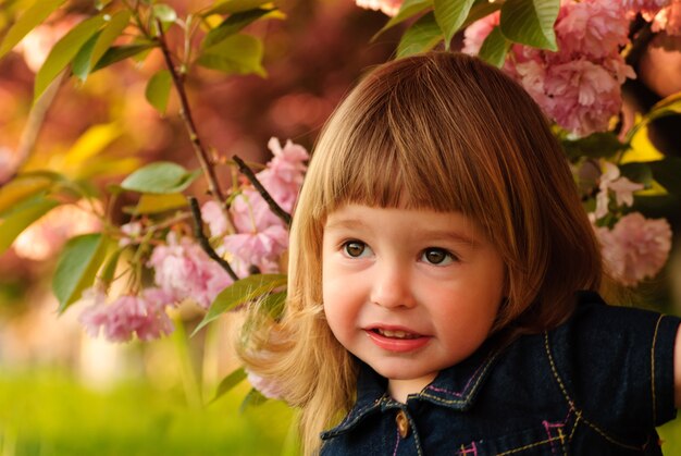 Petite fille dans le jardin sous l'arbre de sakura