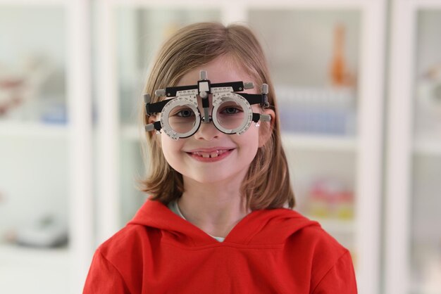 Petite fille dans des lunettes d'ophtalmologie pour la correction de la vue regarde à huis clos souriant positif