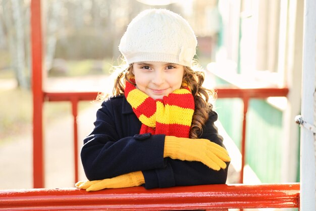 Petite fille dans un manteau bleu avec une écharpe colorée dans le parc en automne. photo de haute qualité