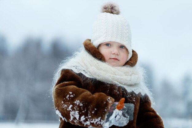 Petite fille dans un manteau de fourrure sur un fond d'hiver