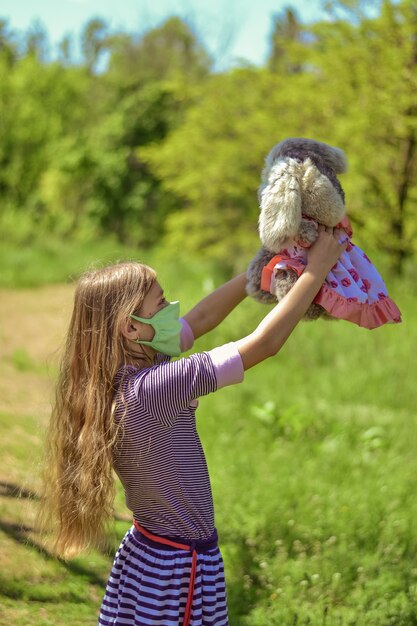 Une petite fille dans un masque de protection joue avec un jouet