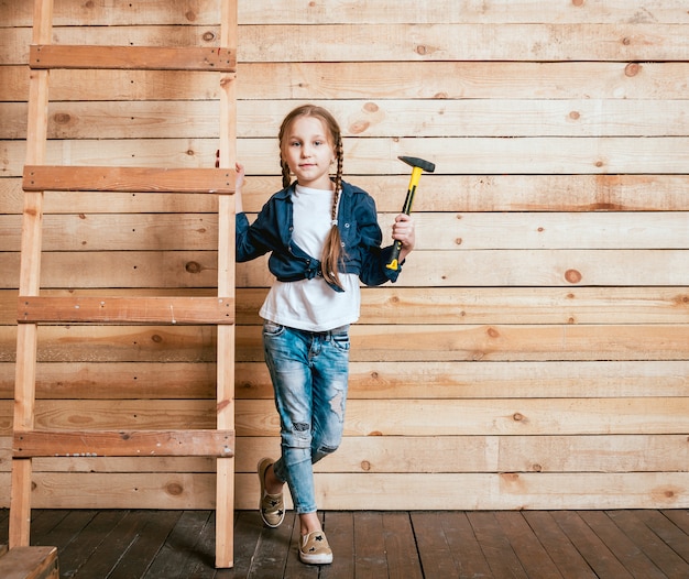 Petite fille dans une pièce avec un mur en bois. Construction