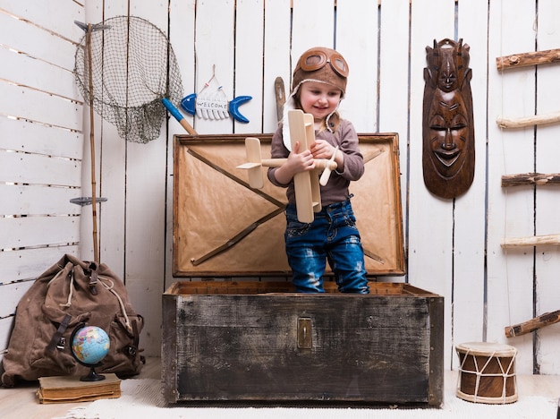 Petite fille dans la poitrine avec un avion en bois dans les mains