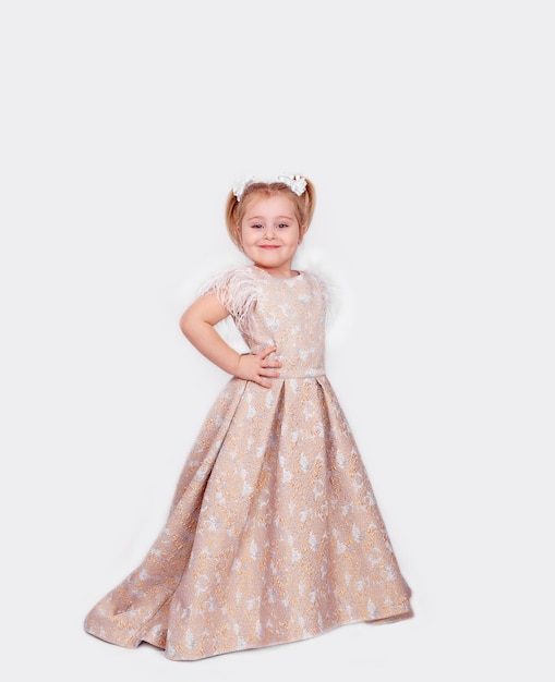 Une petite fille dans une robe de bal pleine longueur sur un fond blanc