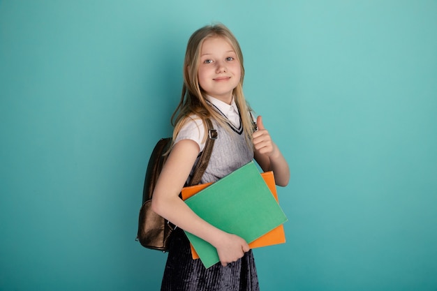 Petite fille dans une robe d'école debout isolé le fond bleu.