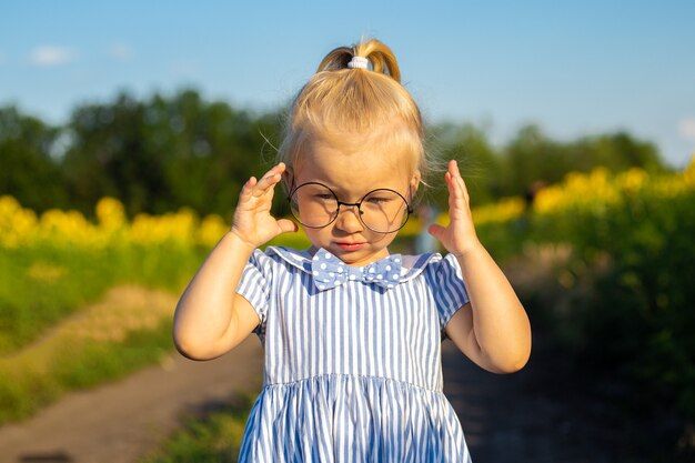 Petite fille dans une robe et des lunettes sur le fond d'un champ de tournesol.