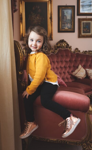 Petite fille dans un salon au décor baroque.