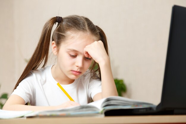 Petite Fille Dans Un T-shirt Blanc Fait Ses Devoirs. Chambre Lumineuse Avec Lumière Du Jour, Fille Indépendante, éducation