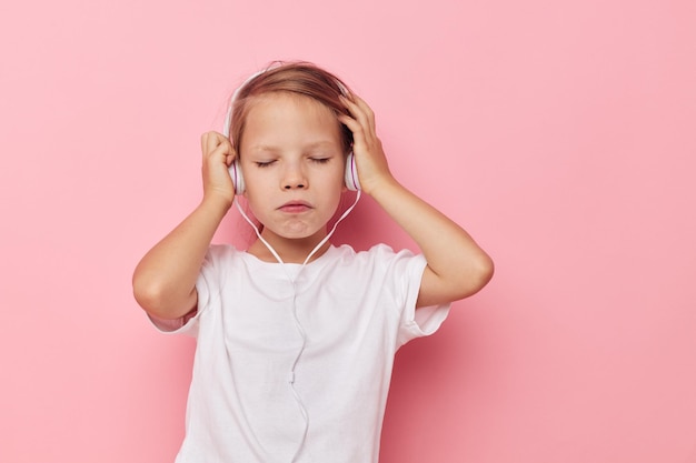 Petite fille dans un t-shirt blanc avec fond rose casque