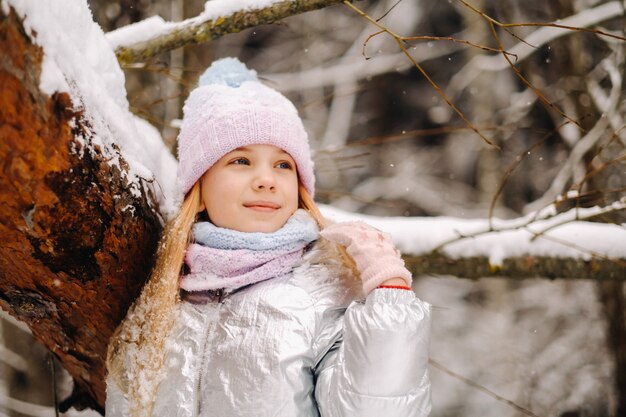 Une petite fille dans une veste argentée en hiver sort dehors en hiver