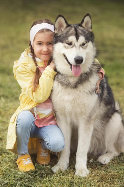 Petite fille dans des vêtements colorés avec son animal de compagnie drôle ami malamute chien d'Alaska