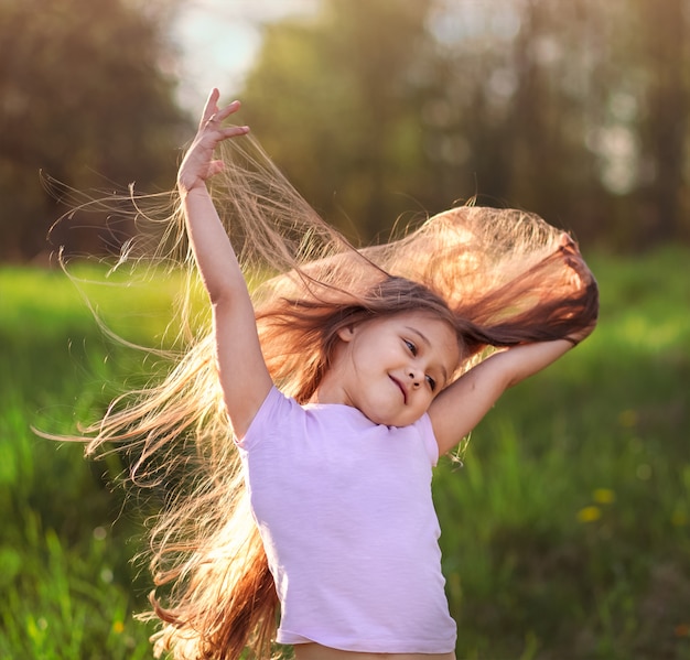 Petite fille dansant dans la nature en été aux cheveux longs