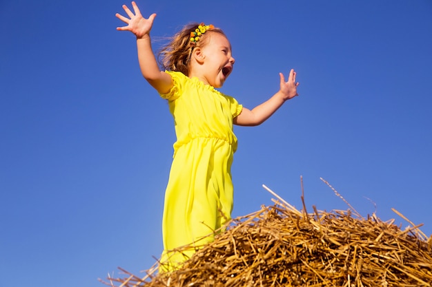 Petite fille debout sur un champ de foin