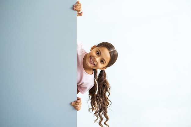 La petite fille debout sur le mur sur fond blanc