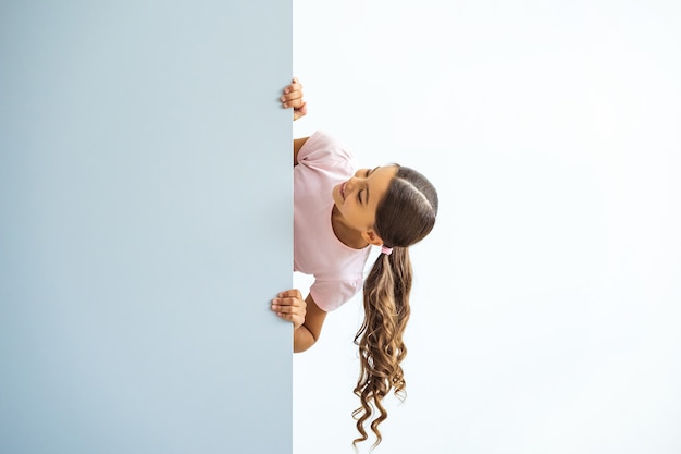 La petite fille debout sur le mur sur fond blanc