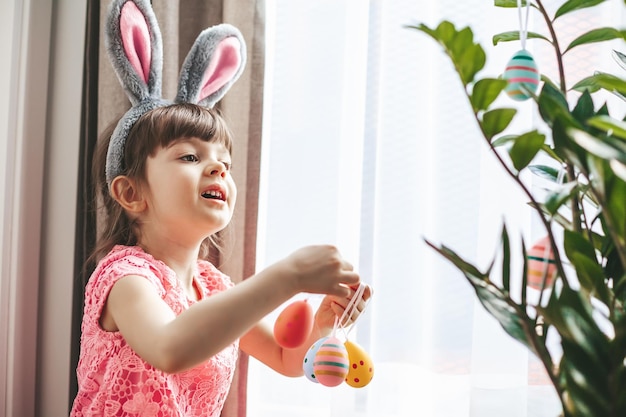 Petite fille décorant une plante pour les vacances de Pâques