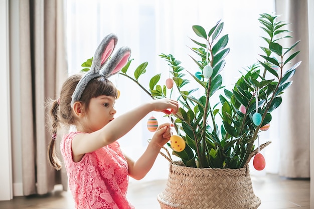 Petite fille décorant une plante pour les vacances de Pâques