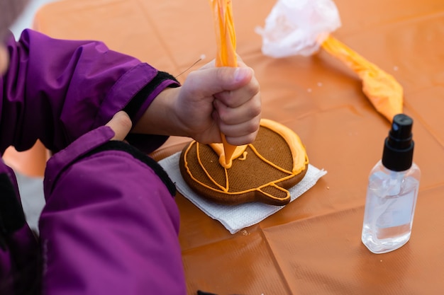 La petite fille décore des biscuits pour Halloween. Projet d'art pour enfants, un artisanat pour les enfants.