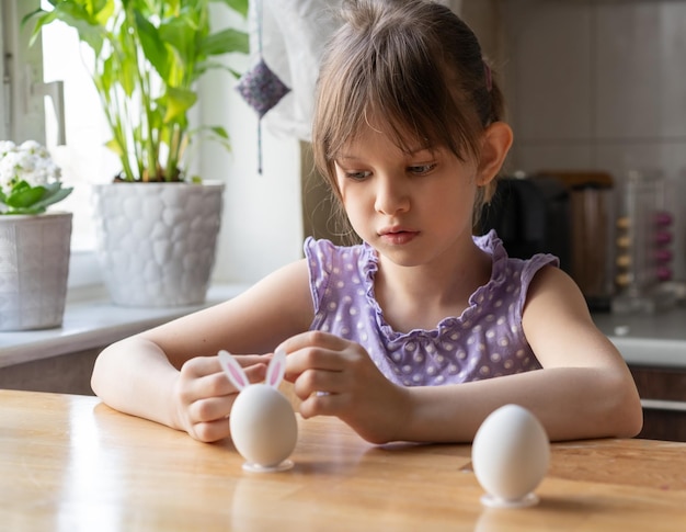 Petite fille décore des œufs de Pâques à la maison se prépare pour le concept de Pâque focus sélectif