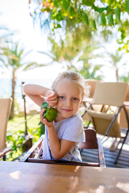 Une petite fille dégustant des dattes vertes dans un verger