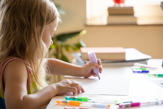 Photo une petite fille dessine assise à la table.