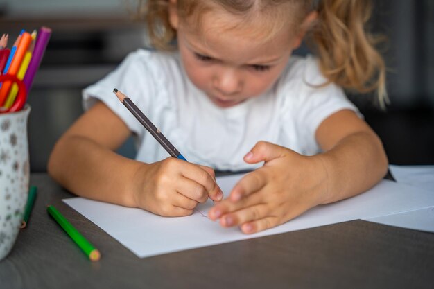 Photo la petite fille dessine avec des crayons de couleur à la maison.