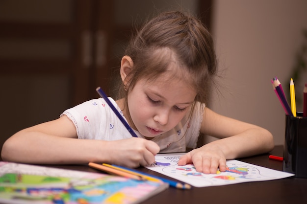 Une petite fille dessine avec des crayons de couleur