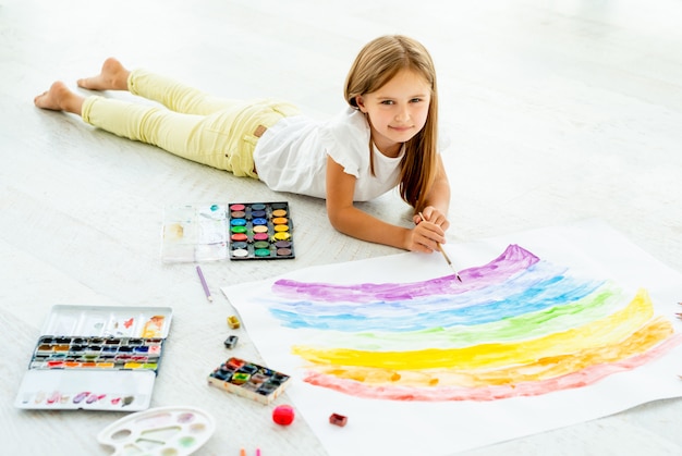 Petite fille dessine gisant sur le solPetite fille gaie dessine gisant sur le sol