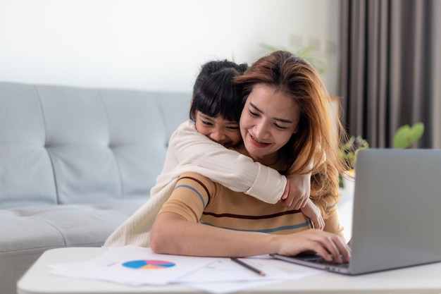 Petite fille donnant un baiser à sa mère en travaillant à domicile