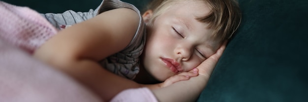 Petite fille dort dans son lit avec ses bras croisés sous sa tête