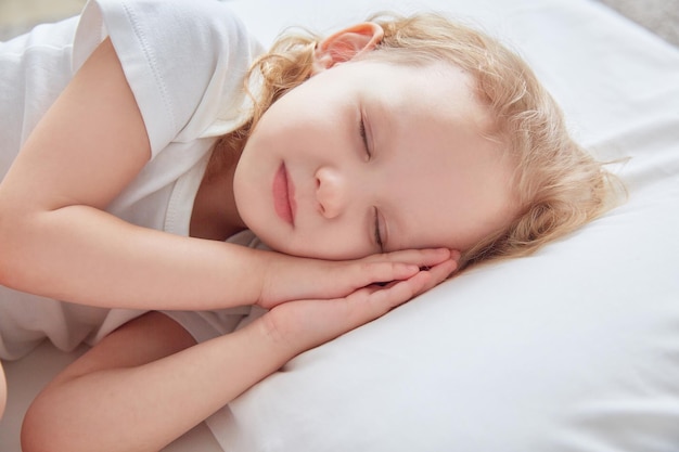 La petite fille dort sur un oreiller blanc