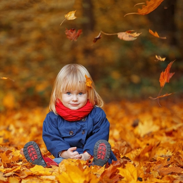 Petite fille drôle d'automne assise dans le parc d'automne Espace de copie de mise au point sélective