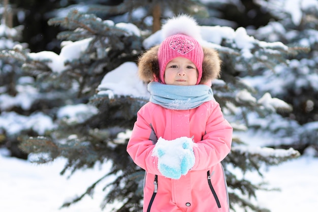 Petite fille drôle d'enfant en bas âge jouant dans des boules de neige. jeu d'hiver d'hiver pour les enfants. Enfant s'amusant le temps de Noël