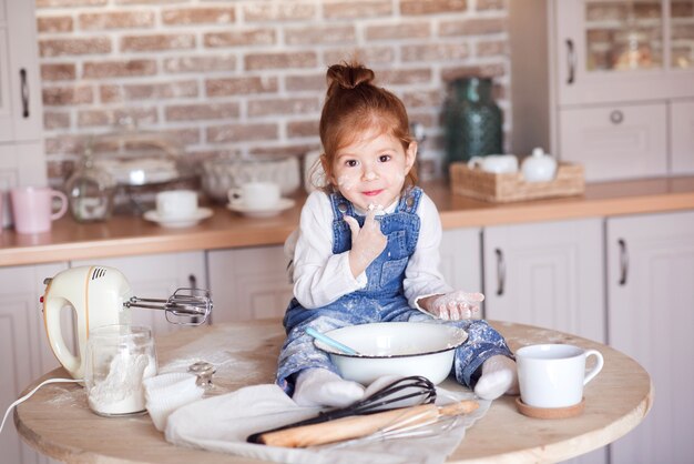 Petite fille drôle faisant un gâteau avec de la farine dans un bol