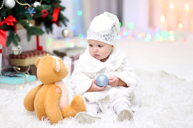 Petite fille drôle avec le jouet de Noël près de l'arbre de Noël