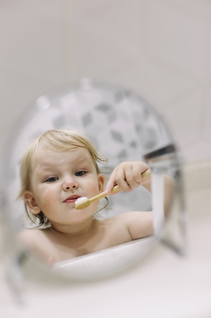 Petite fille drôle se brosser les dents dans la salle de bain