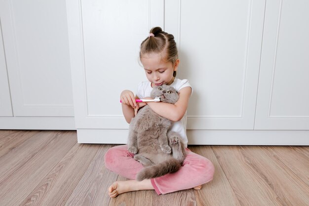 La petite fille drôle se brosser les dents du chat avec une brosse à dents Concept de santé de l'animal Higiene buccale