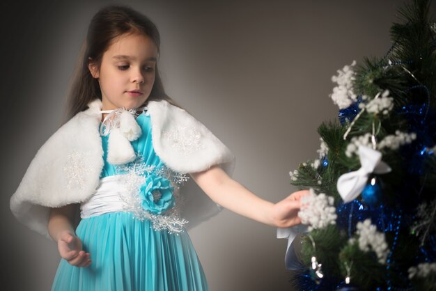 La petite fille avec du charme décore un arbre de Noël