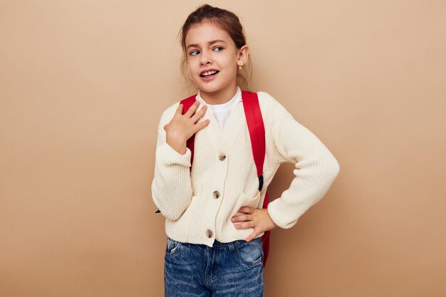 Petite fille écolière avec sac à dos rouge posant l'enfance inchangée