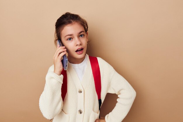 Petite fille écolière sac à dos téléphone en main fond isolé