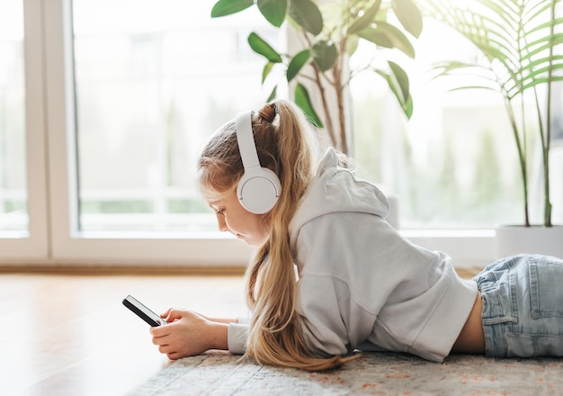 Une petite fille écoutant de la musique allongée sur le sol.