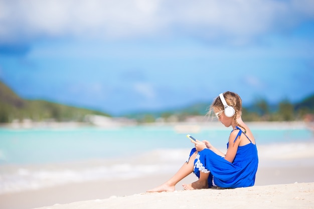 Petite fille écoutant de la musique au casque sur la plage