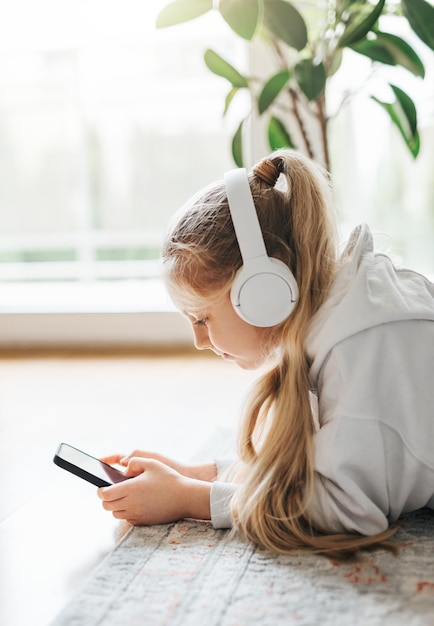 Petite fille écoutant de la musique gisant sur le sol