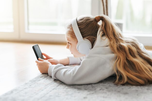 Petite fille écoutant de la musique gisant sur le sol