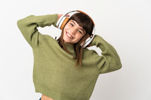 Petite fille écoutant de la musique avec un mobile isolé sur un mur blanc à l'écoute de la musique