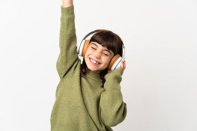 Petite fille écoutant de la musique avec un mobile isolé sur un mur blanc, écouter de la musique et danser