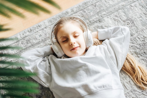 Une petite fille écoute de la musique allongée sur le sol.
