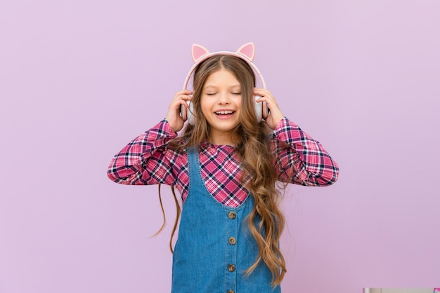 Une petite fille écoute de la musique avec un casque un enfant sur un fond isolé dans un casque rose