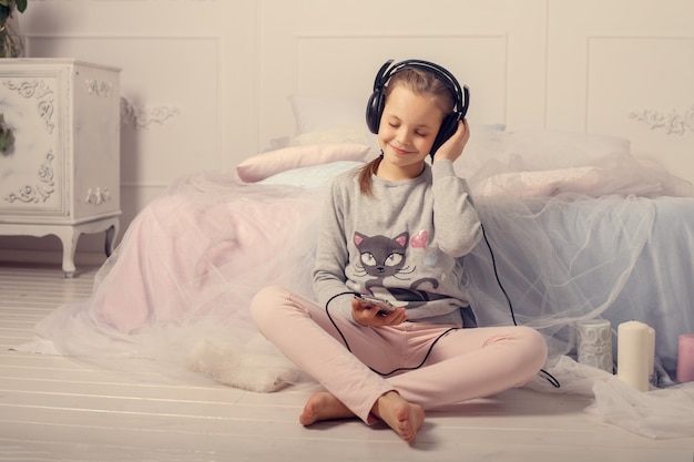 La petite fille écoute de la musique dans la pièce.