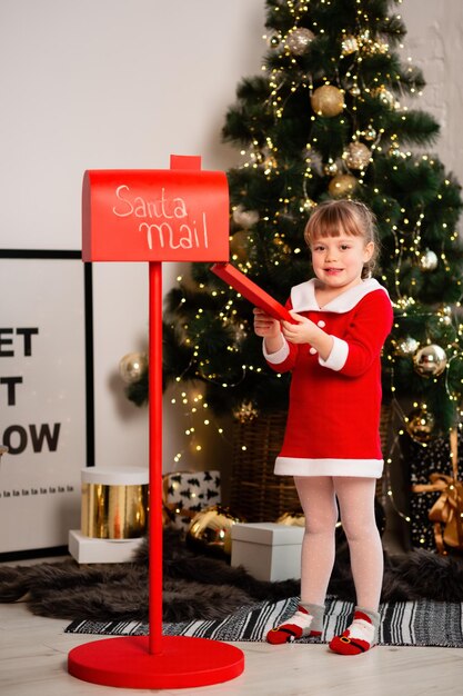 Une petite fille a écrit une lettre au Père Noël avec des souhaits et l'a mise dans une boîte rouge Focus sur l'enfant